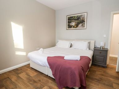 A bedroom with a double bed bedside table and a framed picture on the wall at Cadwaladr in Bontnewydd near Caernarfon