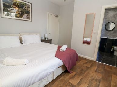 A bedroom with a double bed a bedside table with a lamp a wall mirror and an open door leading to a bathroom at Cadwaladr in Bontnewydd near Caernarfon