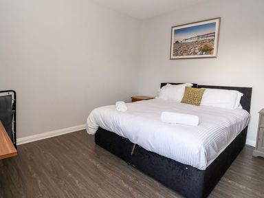 A bedroom with a bed towels on it a bedside table a desk and a framed picture on the wall at Cadwaladr in Bontnewydd near Caernarfon