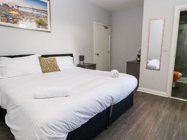A bedroom with a double bed two bedside tables a tall mirror and a door to a bathroom at Cadwaladr in Bontnewydd near Caernarfon