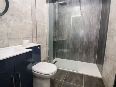 A bathroom with a toilet a sink and a glass shower enclosure at Cadwaladr in Bontnewydd near Caernarfon