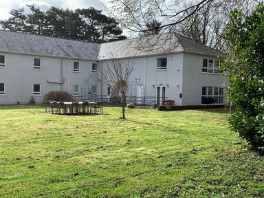 A grassy backyard with outdoor dining table and chairs near a two-story building at Cadwaladr in Bontnewydd near Caernarfon