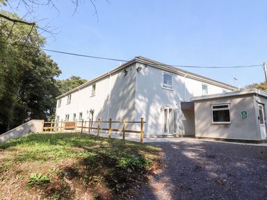 A two-story white building with multiple windows a small fenced grassy area and a gravel driveway at Cadwaladr in Bontnewydd near Caernarfon