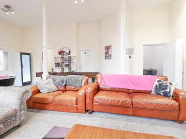 A living room with two brown leather sofas a pool table and a bookshelf at The Lombard in Dolgellau