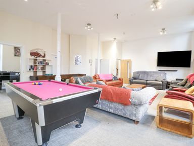 A recreation room with a pink pool table sofas a large wall mounted television and a wooden side table at The Lombard in Dolgellau