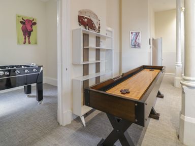 A game room with a shuffleboard table and foosball table and wall decorations at The Lombard in Dolgellau