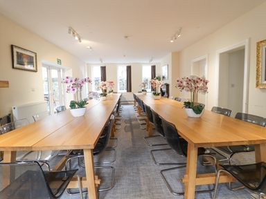A dining room with two long wooden tables and black chairs with flower arrangements at The Lombard in Dolgellau