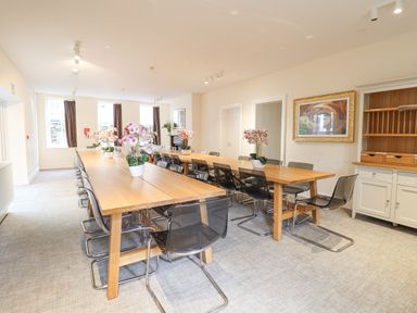 A dining room with two wooden tables and black chairs with flower pots on the tables at The Lombard in Dolgellau
