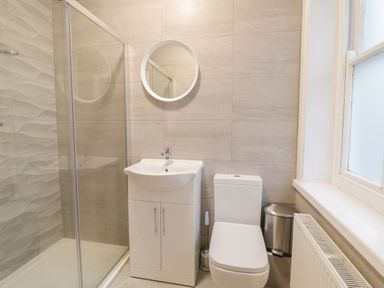 A bathroom with a shower enclosure sink cabinet toilet mirror and window at The Lombard in Dolgellau