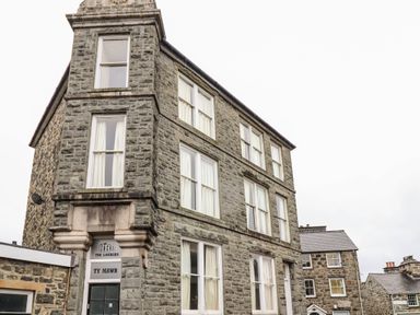 A stone building with multiple windows and white curtains at The Lombard in Dolgellau