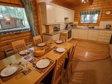 A kitchen and dining area with wooden table set for six and white cabinets at Bamboo Retreat in Louth