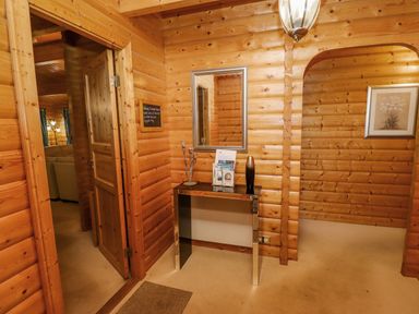 A wooden hallway with a mirror above a table and an open door showing a room with a sofa at Bamboo Retreat in Louth