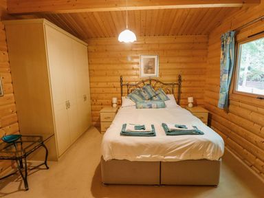 A bedroom with a double bed two bedside tables a wardrobe and a window with curtains at Bamboo Retreat in Louth