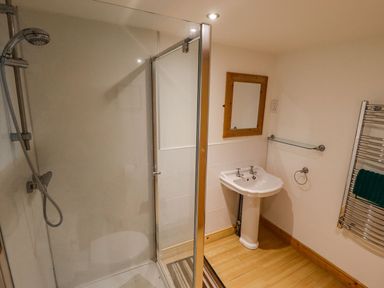 A bathroom with a shower enclosure a white sink with separate taps a wooden framed mirror and a heated towel rail at Bamboo Retreat in Louth