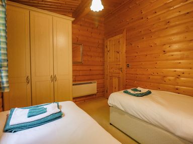 A bedroom with two single beds a wooden wardrobe and a wooden door at Bamboo Retreat in Louth