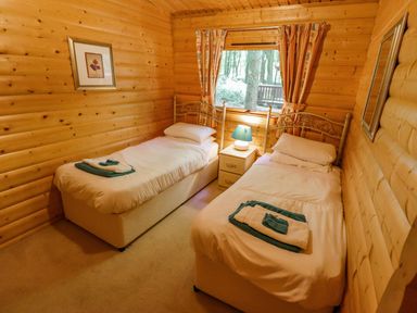 A bedroom with two single beds and a bedside table with a lamp at Bamboo Retreat in Louth