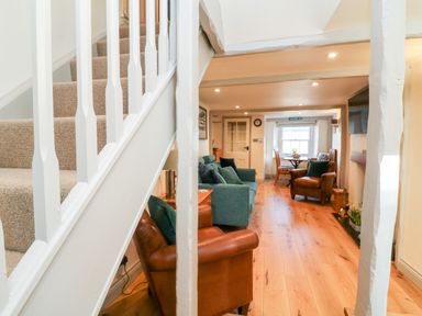 A sitting area with leather armchairs a blue sofa wooden floor and stairs at Peppers Cottage in Appledore