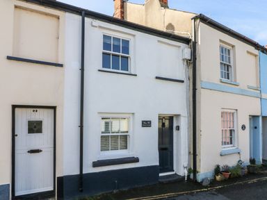 Exterior of a row of terraced houses with numbered doors and windows on a street at Peppers Cottage in Appledore