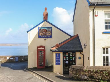 Exterior of a building with a red phone booth and a sign that reads The Beaver Inn near a waterfront