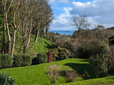 A garden with bushes and trees overlooking the sea at Mariners Rest in Gorran Haven