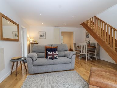 A living room with a sofa and dining area at Mariners Rest in Gorran Haven