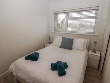 A bedroom with a double bed white bedding and blue towels on the bed with side tables and lamps at 16 Coedrath Park in Saundersfoot