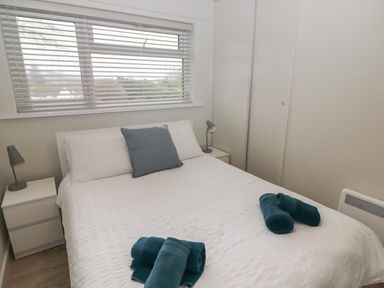 A bedroom with a double bed two bedside tables with lamps and rolled towels on the bed at 16 Coedrath Park in Saundersfoot