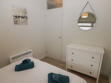 A bedroom with a white dresser mirror on the wall above and folded towels on the bed at 16 Coedrath Park in Saundersfoot