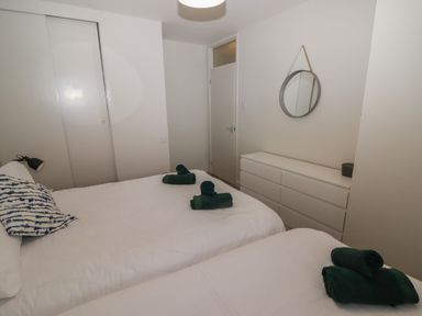 A bedroom with two beds white dresser and round mirror at 16 Coedrath Park Saundersfoot