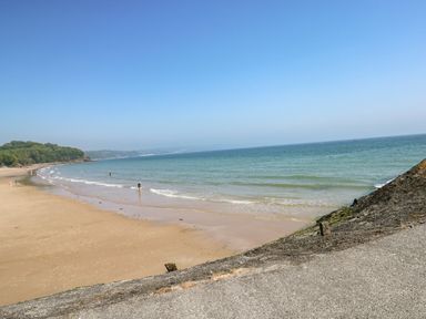 A sandy beach with people near the water and green hills in the background at 36 Coedrath Park in Saundersfoot