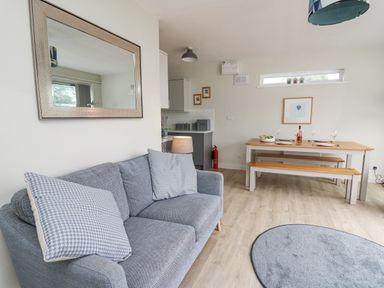 A living room with a sofa and dining table with benches at 36 Coedrath Park in Saundersfoot