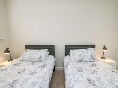 A bedroom with two single beds with animal print bedding two bedside tables and black lamps at 36 Coedrath Park in Saundersfoot