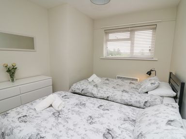 A bedroom with two single beds a dresser a mirror and a window at 36 Coedrath Park Saundersfoot