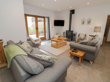 A living room with two grey sofas a wood-burning stove and a wooden coffee table at The Stables in Droitwich Spa