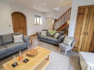 A living room with two grey sofas a grey chair and a wooden coffee table at The Stables in Droitwich Spa
