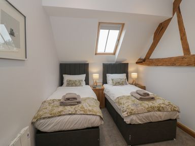 A bedroom with two single beds bedside tables lamps and a skylight window at The Stables in Droitwich Spa