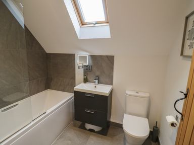 A bathroom with a bathtub a sink and a toilet under a skylight at The Stables in Droitwich Spa