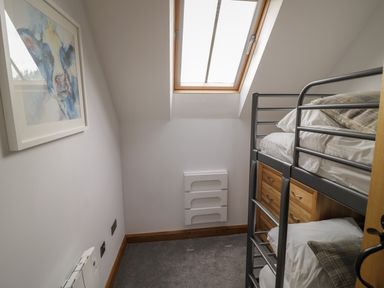 A small bedroom with a bunk bed under a skylight window and a painting on the wall at The Stables in Droitwich Spa