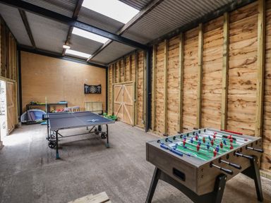 A game room with a ping pong table foosball table dartboard and toys at The Stables in Droitwich Spa