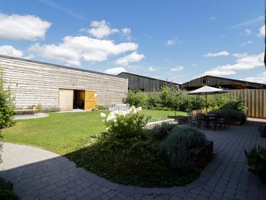 A garden with a lawn patio furniture and a wooden building at The Stables in Droitwich Spa
