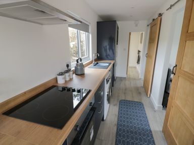 A kitchen with a cooktop oven washing machine sink and kettle at Goldthorne Lodge in Clee Hill