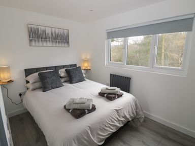 A bedroom with a double bed with pillows and folded towels near a window at Goldthorne Lodge in Clee Hill