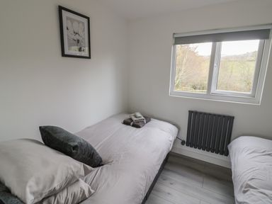 A bedroom with two single beds a window and a framed flower picture on the wall at Goldthorne Lodge in Clee Hill