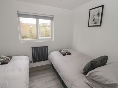 A bedroom with two single beds a window and a framed flower picture on the wall at Goldthorne Lodge in Clee Hill