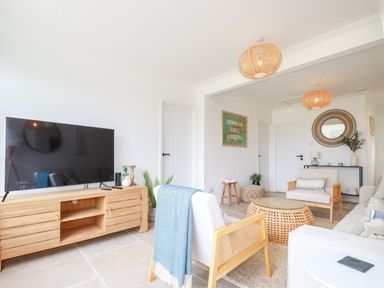 A living room with wooden furniture a television and a sign on the wall at Polwen in Harlyn Bay Padstow