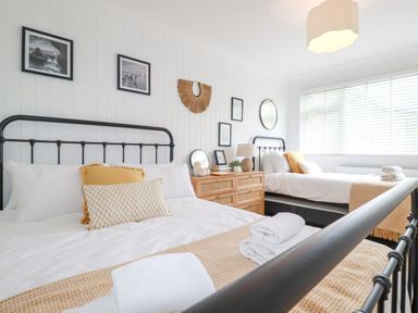 A bedroom with two beds and a wooden dresser with decorations at Polwen in Harlyn Bay Padstow