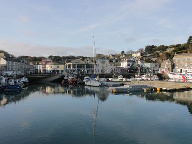A harbor with boats docked and buildings in the background at Polwen in Harlyn Bay Padstow