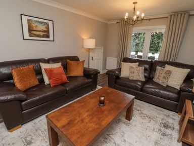 A living room with two brown leather sofas a wooden coffee table and a floor lamp at Sparrow House in Alnwick