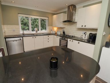 A kitchen with black countertops white cabinets a window and various appliances at Sparrow House in Alnwick