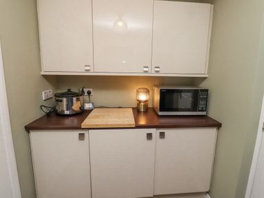 A kitchen countertop with a slow cooker microwave wooden cutting board and a lamp at Sparrow House in Alnwick